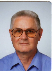 Photo of Klaus Daube: blue shirt, goat beard, large glasses with narrow border, hair with Navy cut